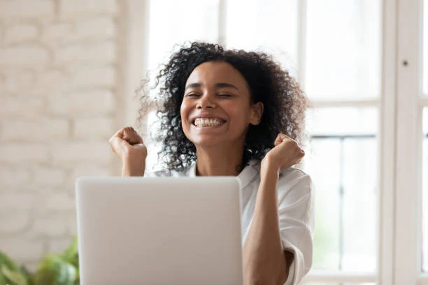 Employee celebrating a successful payroll payment while working on a laptop.